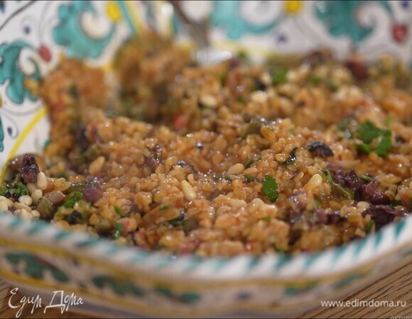 Выложить булгур в глубокую тарелку, добавить оливки, каперсы и зелень, полить все оливковым маслом и выжатым из половинки лимона соком, посыпать орехами и перемешать.