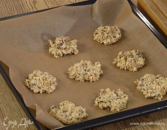 Сформировать из овсяной массы небольшие лепешки и выложить их на выстеленный бумагой для выпечки противень.