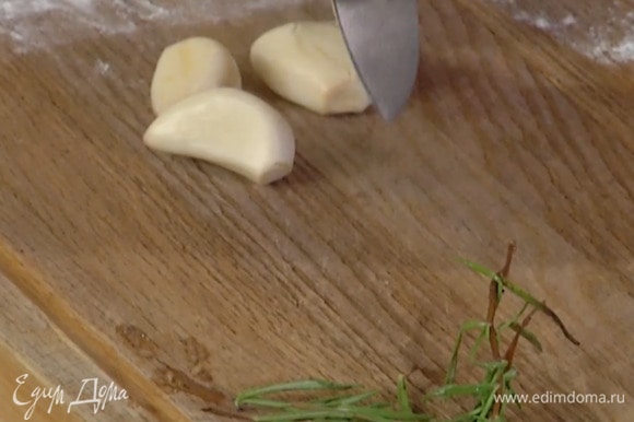 Чеснок почистить, раздавить плоской стороной ножа и выложить на мясо, добавить веточки розмарина (одну оставить) и накрыть мясо фольгой, скрепив края.