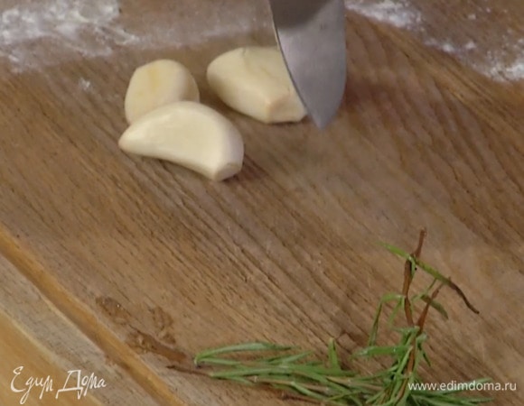 Чеснок почистить, раздавить плоской стороной ножа и выложить на мясо, добавить веточки розмарина (одну оставить) и накрыть мясо фольгой, скрепив края.