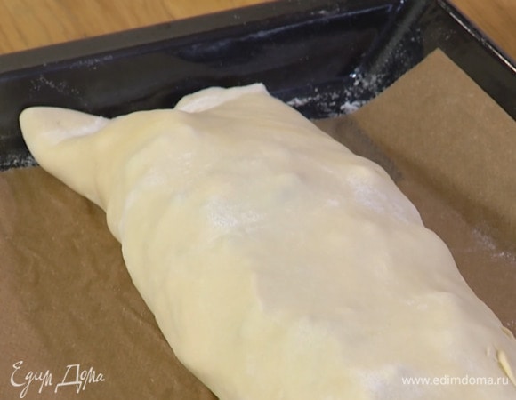 Тесто раскатать на присыпанной мукой рабочей поверхности в тонкий пласт и переложить на выстеленный бумагой для выпечки противень, разложить овощи, отступая немного от краев, и свернуть в рулет по длинной стороне. Скрепить края и боковые части.