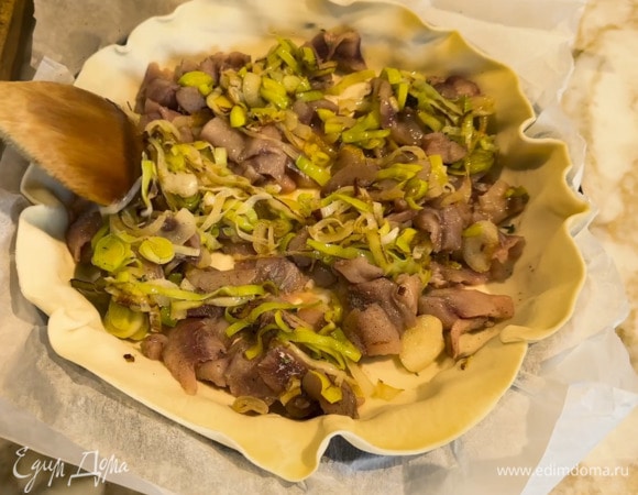 Форму выстелить бумагой для выпечки, выложить пласт теста, сверху разложить рыбу и обжаренный лук с чесноком, все посолить, поперчить, посыпать листьями чабреца и сухарями.