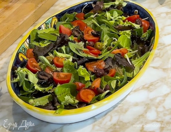 Приготовить салат: на широкую тарелку выложить салатные листья, помидоры, оливки и фету, полить заправкой, посыпать порванным руками базиликом, грецкими орехами, сбрызнуть ореховым маслом.