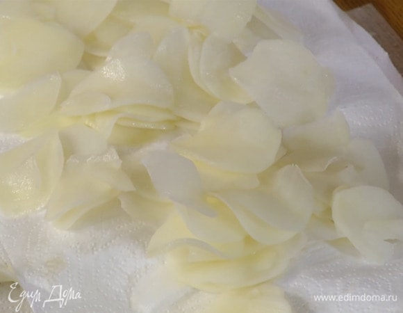 Картофель почистить, нарезать тонкими ломтиками, залить водой и дать постоять, затем воду слить, картофель промокнуть бумажным полотенцем.