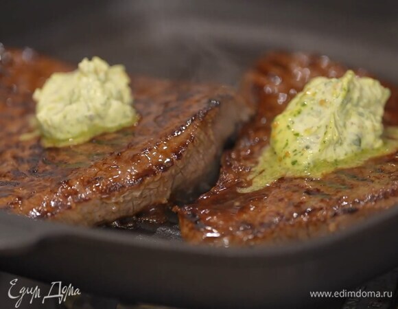 Когда мясо будет практически готово, выложить на каждый кусок по 1–2 ч. ложки зеленого масла и снять сковороду с огня.