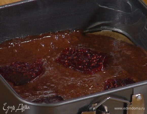 Квадратную форму со съемным дном выстелить бумагой для выпечки, смазать оставшимся сливочным маслом и выложить половину шоколадного теста, на него разложить чайной ложкой малиновый джем.