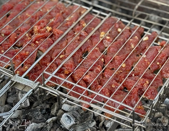 Положите говядину в решетку-гриль. Готовьте ее на раскаленных углях по 2–3 минуты.