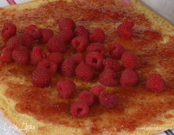 Смазать весь пласт джемом, разложить малину (несколько ягод оставить) и свернуть в рулет по длинной стороне.