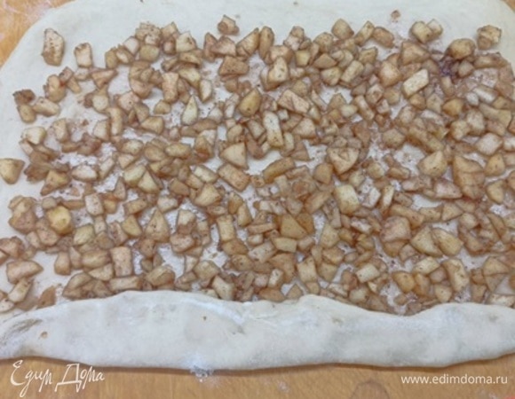 Яблоки откинуть на дуршлаг, чтобы стек сок. Подошедшее тесто раскатать в квадрат примерно 50 х 50 см. Выложить яблоки и распределить начинку, оставляя по боками свободными по 2 см.