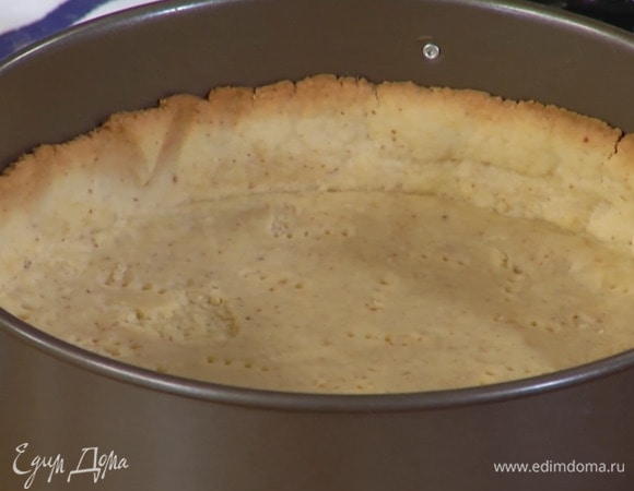 Дно разъемной формы выстелить бумагой для выпечки и выложить тесто, сформировав тонкий корж с бортиками, затем часто наколоть его вилкой, накрыть бумагой для выпечки, всыпать любые бобовые для груза и выпекать в разогретой духовке 15–20 минут.