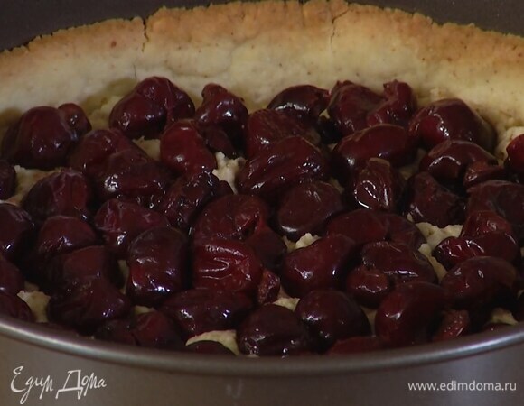 С подпеченного коржа снять бобовые с бумагой, равномерно выложить миндальную начинку, а сверху вишню.