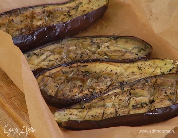 Баклажаны разрезать вдоль пополам и острым ножом надрезать внутри косыми линиями, затем выложить в небольшой противень, выстеленный бумагой для выпечки, посолить, поперчить, слегка сбрызнуть оливковым маслом, сверху разложить веточки тимьяна и запекать в разогретой духовке 20 минут.