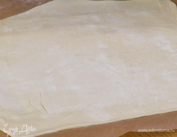 Тесто выложить на бумагу для выпечки, слегка посыпать мукой и тонко раскатать.