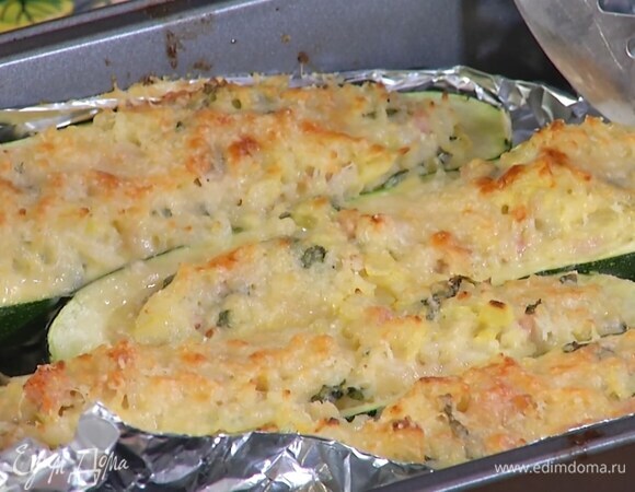 Небольшую форму для запекания выстелить фольгой, выложить половинки цукини, наполнить их рисовой начинкой, посыпать оставшимся сыром и запекать в разогретой духовке 15 минут.