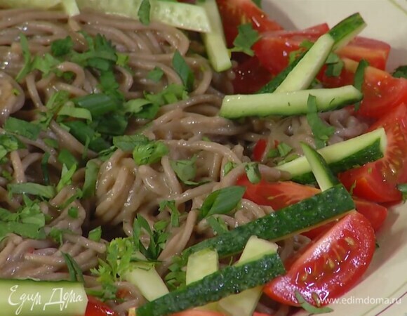 Готовую лапшу выложить в глубокую миску, влить оставшееся растительное масло, полить заправкой, перемешать, затем выложить сверху помидоры, огурцы и посыпать все зеленью и кунжутом.