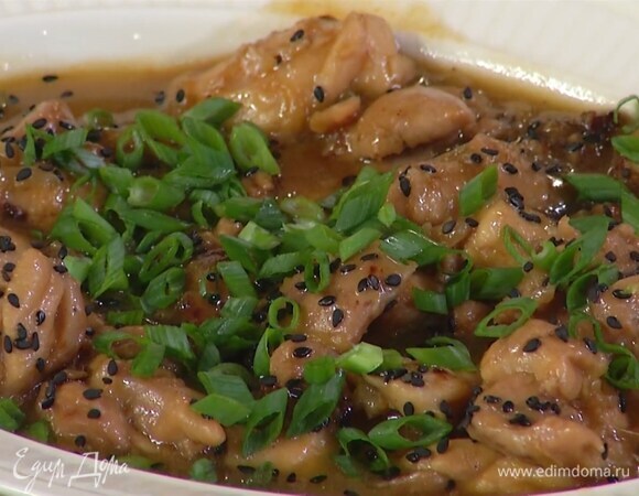 Выложить готовую курицу в глубокую миску, посыпать измельченным зеленым луком и кунжутом.