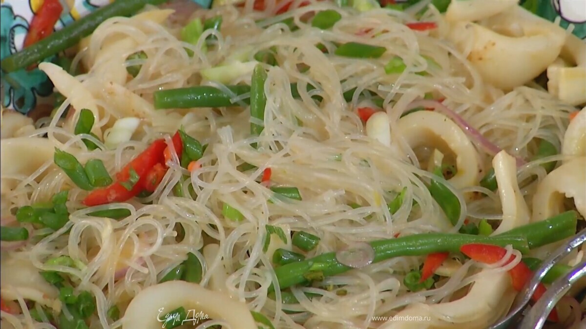 В салатник выложить фунчозу в заправке и полоски кальмаров, полить все соевым соусом, перемешать, посыпать зеленым луком.