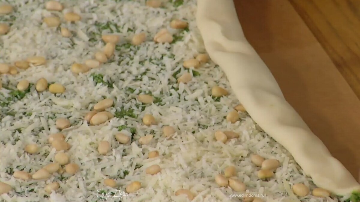 Размороженное тесто тонко раскатать, равномерно смазать соусом песто, посыпать сыром, орехами и свернуть по длинной стороне в рулет.