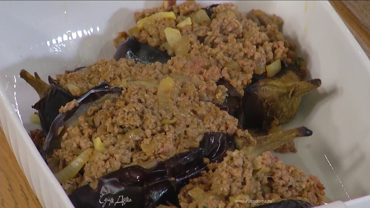 Обжаренные баклажаны надрезать до середины с одной стороны, слегка порубить мякоть внутри, полить оставшимся оливковым маслом, посыпать перцем чили, солью и поместить в жаропрочную керамическую форму, в разрезы баклажанов выложить фарш.