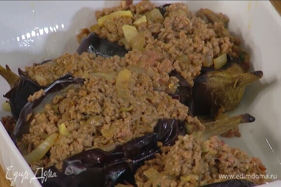 Обжаренные баклажаны надрезать до середины с одной стороны, слегка порубить мякоть внутри, полить оставшимся оливковым маслом, посыпать перцем чили, солью и поместить в жаропрочную керамическую форму, в разрезы баклажанов выложить фарш.