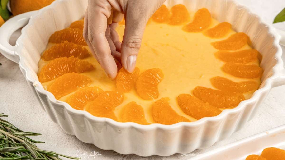 Смажьте форму 20–24 см маргарином. Выложите тесто, сверху положите дольки мандаринов, слегка вдавливая их в тесто.