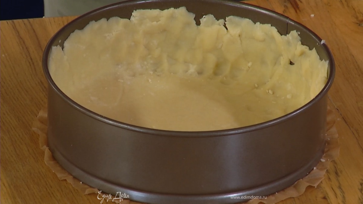 Раскатать тесто между двумя листами бумаги для выпечки, выложить его в разъемную форму, выстеленную пекарской бумагой, и сформировать бортики.