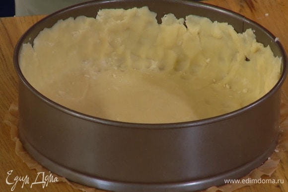 Раскатать тесто между двумя листами бумаги для выпечки, выложить его в разъемную форму, выстеленную пекарской бумагой, и сформировать бортики.