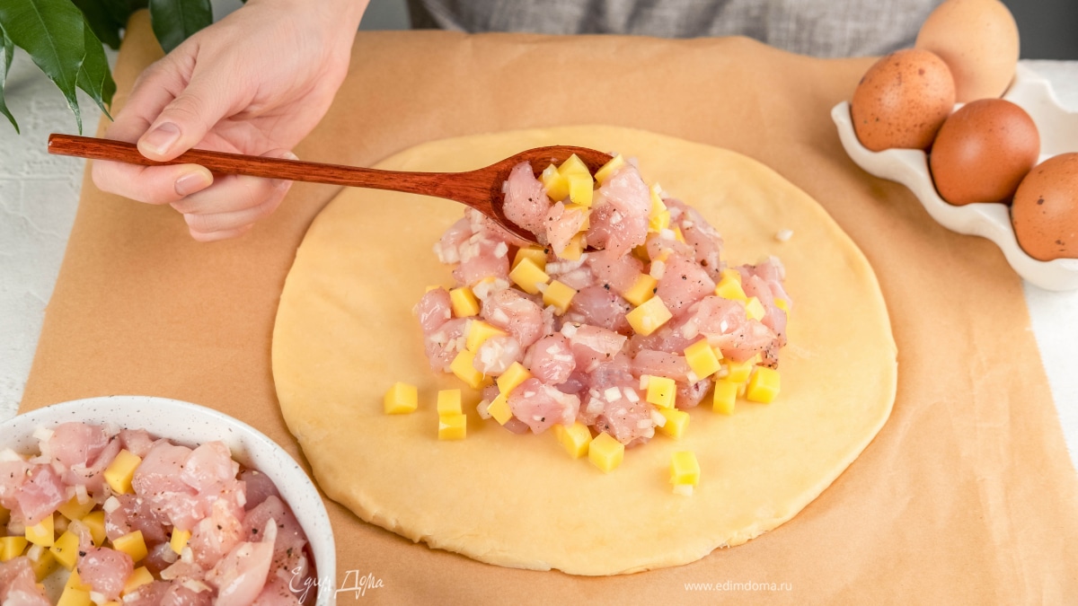 Разделите тесто на две части. Одну раскатайте, и положите ее на противень, застеленный пергаментом. Добавьте начинку.