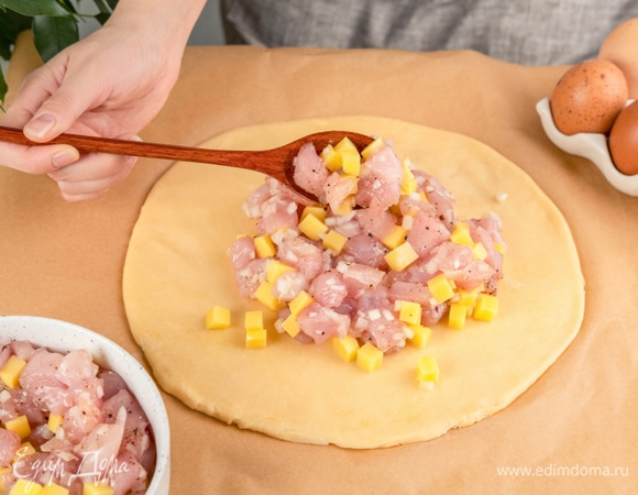 Разделите тесто на две части. Одну раскатайте, и положите ее на противень, застеленный пергаментом. Добавьте начинку.