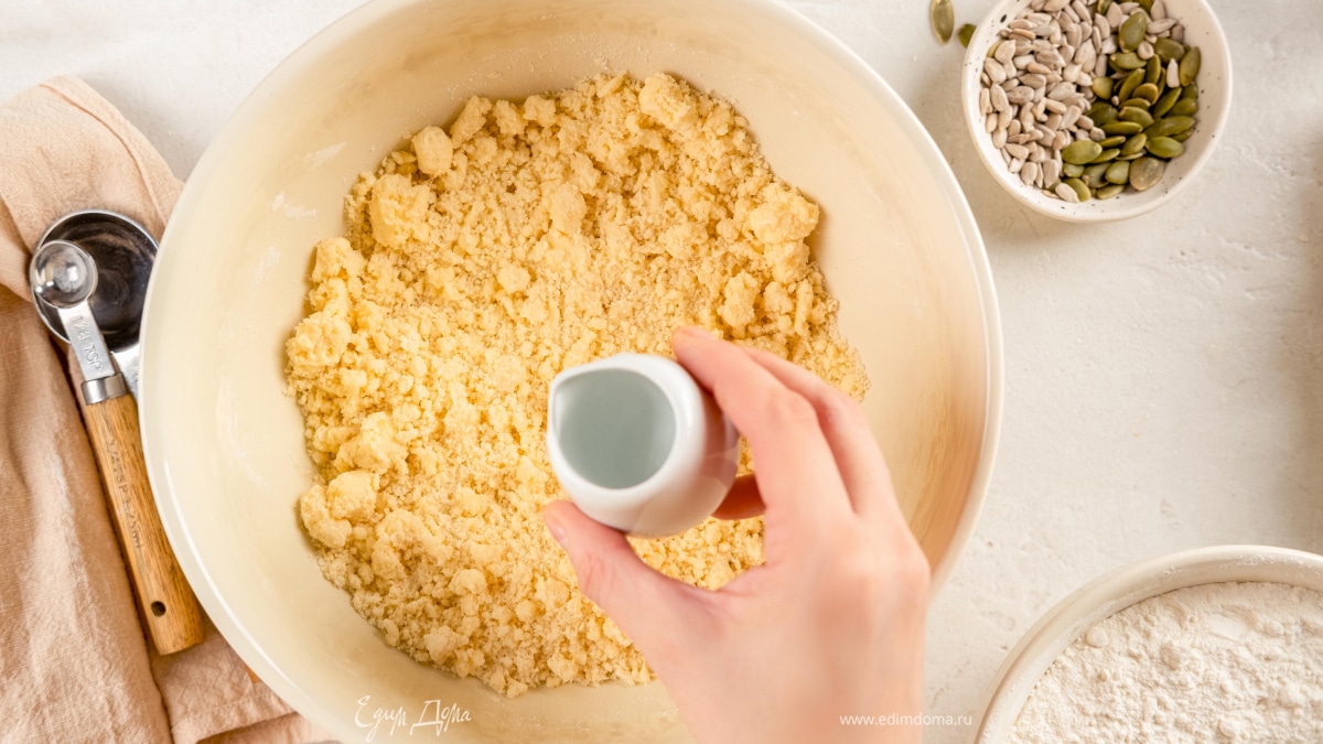 Как только мука с маргарином превратится в крошку, влейте 50 мл воды. Замешайте тесто еще раз и сформируйте шар.