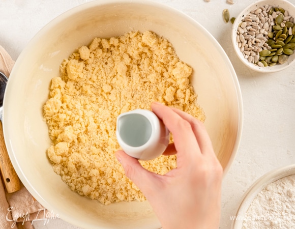 Как только мука с маргарином превратится в крошку, влейте 50 мл воды. Замешайте тесто еще раз и сформируйте шар.