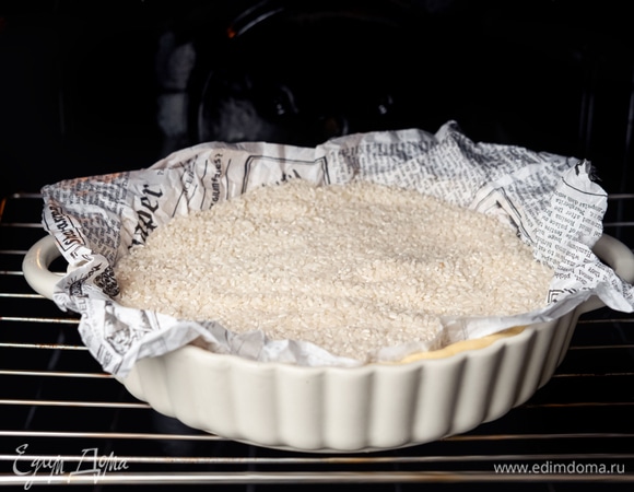 Накройте тесто пергаментной бумагой и положите на него груз. Выпекайте в разогретой духовке при 180°C 20 минут.