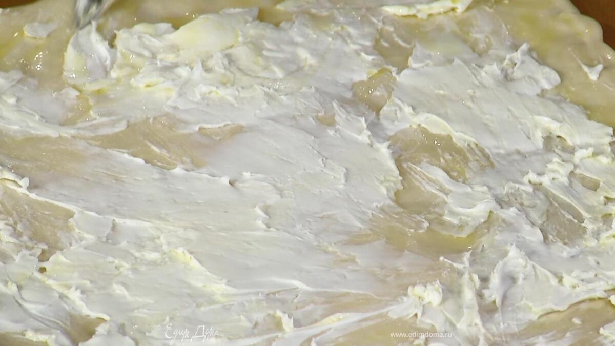 Тесто растянуть руками или раскатать на бумаге для выпечки, смазать оливковым маслом Extra Virgin, а затем сливочным сыром.