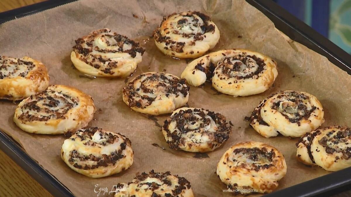 С помощью бумаги для выпечки свернуть тесто в плотный рулет, затем нарезать его небольшими кусочками, выложить на выстеленный бумагой для выпечки противень, смазать желтком с солью и выпекать в разогретой духовке 12–15 минут.