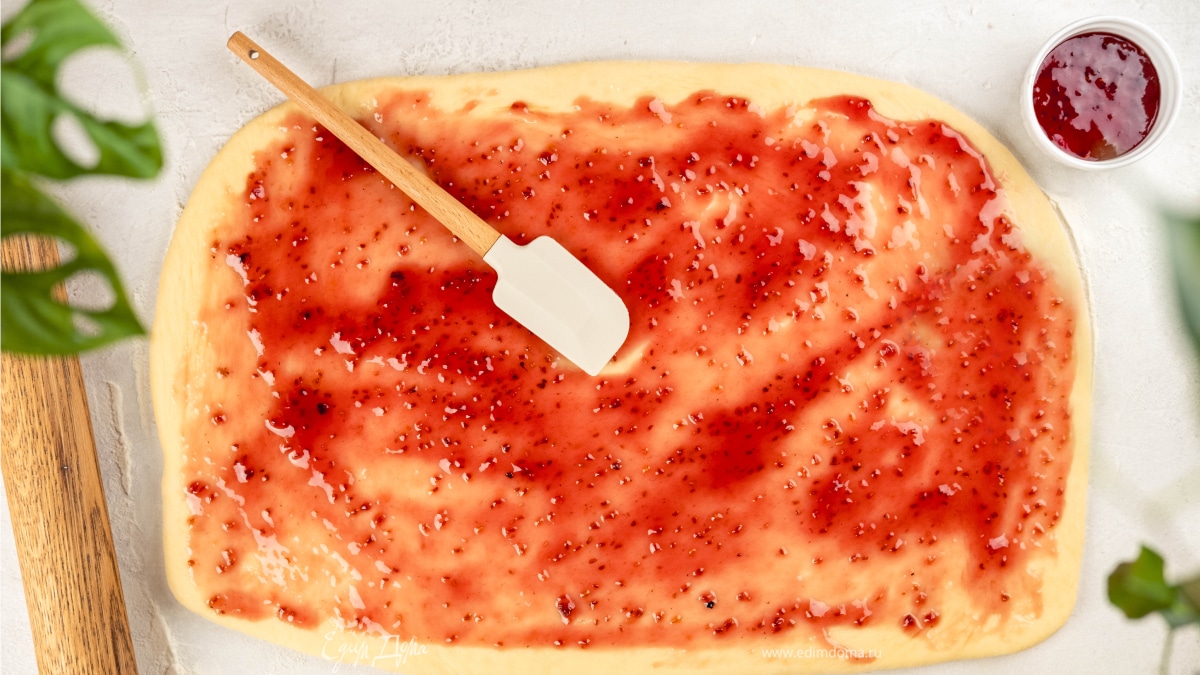 Раскатайте тесто и смажьте его малиновым джемом. Сложите тесто втрое. Затем защипните края и слегка прокатайте скалкой по поверхности. Сформируйте рулетик.