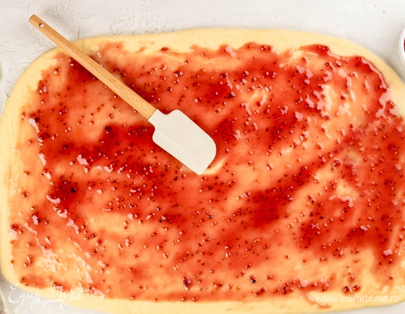 Раскатайте тесто и смажьте его малиновым джемом. Сложите тесто втрое. Затем защипните края и слегка прокатайте скалкой по поверхности. Сформируйте рулетик.