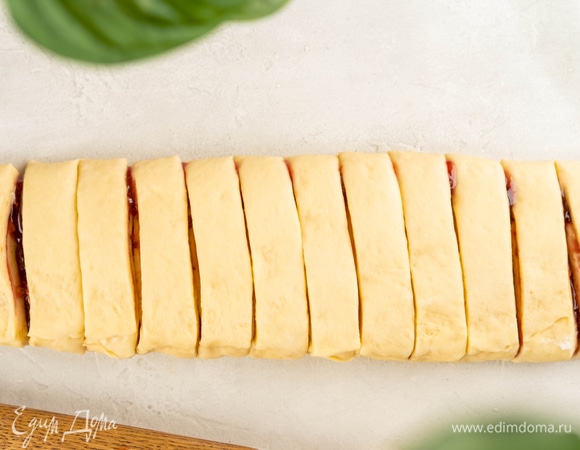 Разрежьте тесто поперек на 12 частей шириной 2,5 см. Перекрутите каждую часть 3–4 раза и сложите колечком, соедините концы.