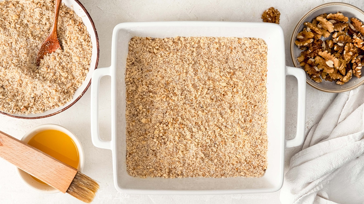 После третьего-четвертого пласта щедро посыпьте смесью орехов и сахара. Продолжайте складывать и смазывать слои.