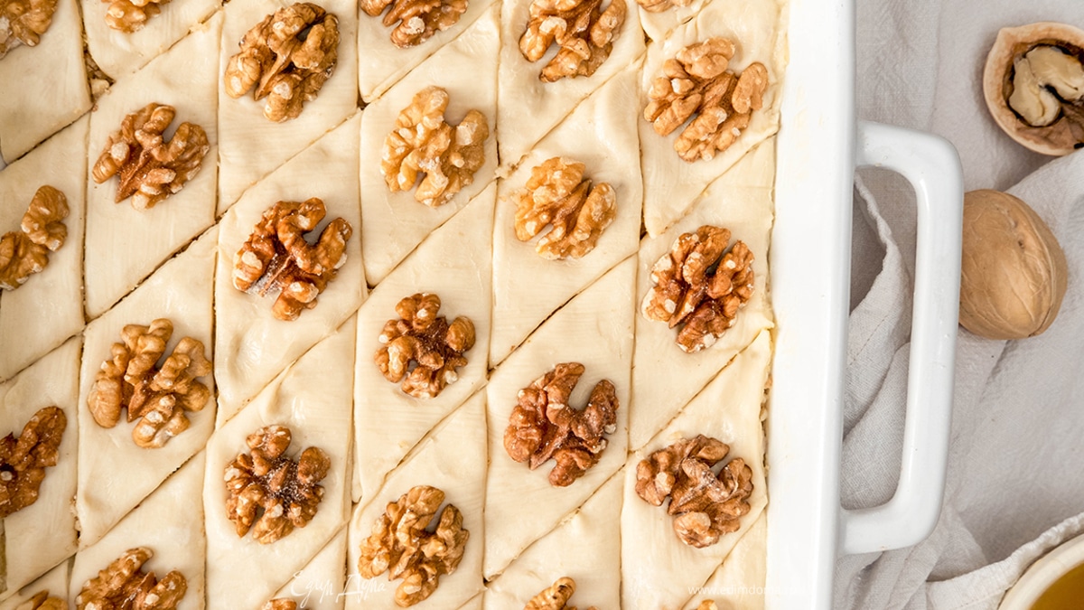 Нарежьте пахлаву на ромбики. Украсьте половинками грецких орехов.