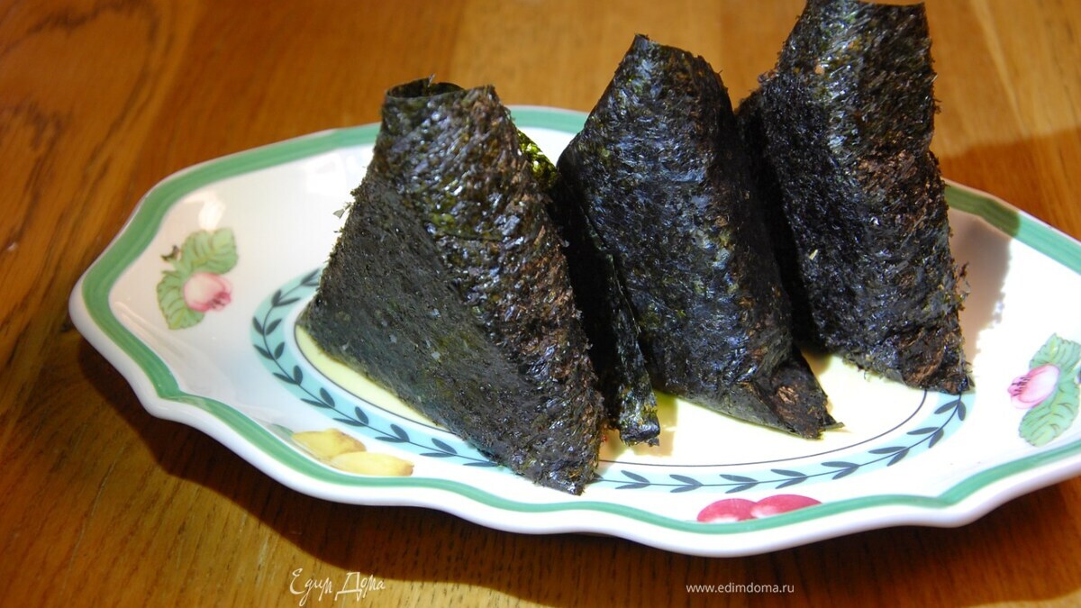 Прижать крышечкой рис в форме и снять ее, слегка смочить уголки нори и свернуть в треугольный конвертик.