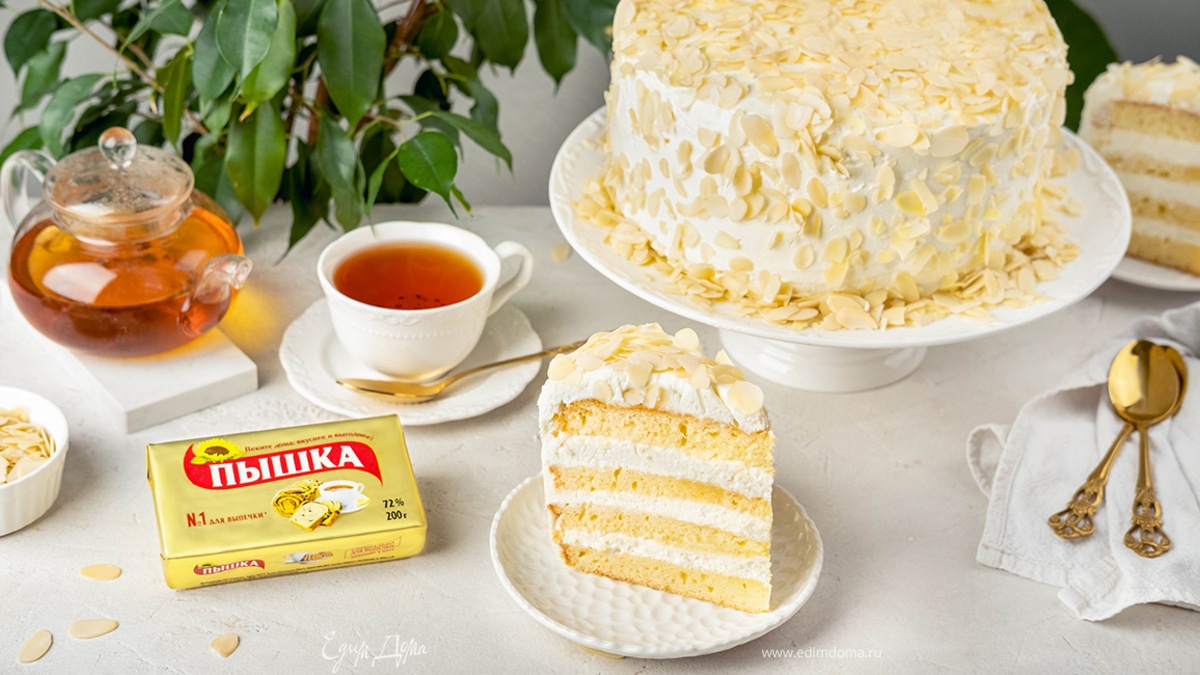 Намажьте оставшийся крем по краям и верхушке торта и посыпьте его миндальными лепестками со всех сторон.