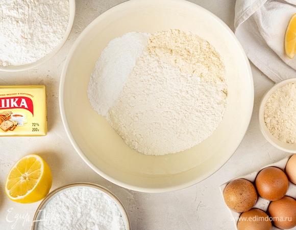 Смешайте два вида муки. Всыпьте сахарную пудру с лимонной цедрой.