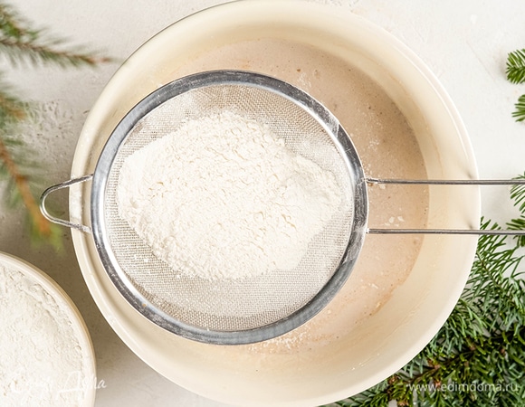 Добавьте дрожжи и постепенно всыпьте муку, замешивая эластичное тесто.