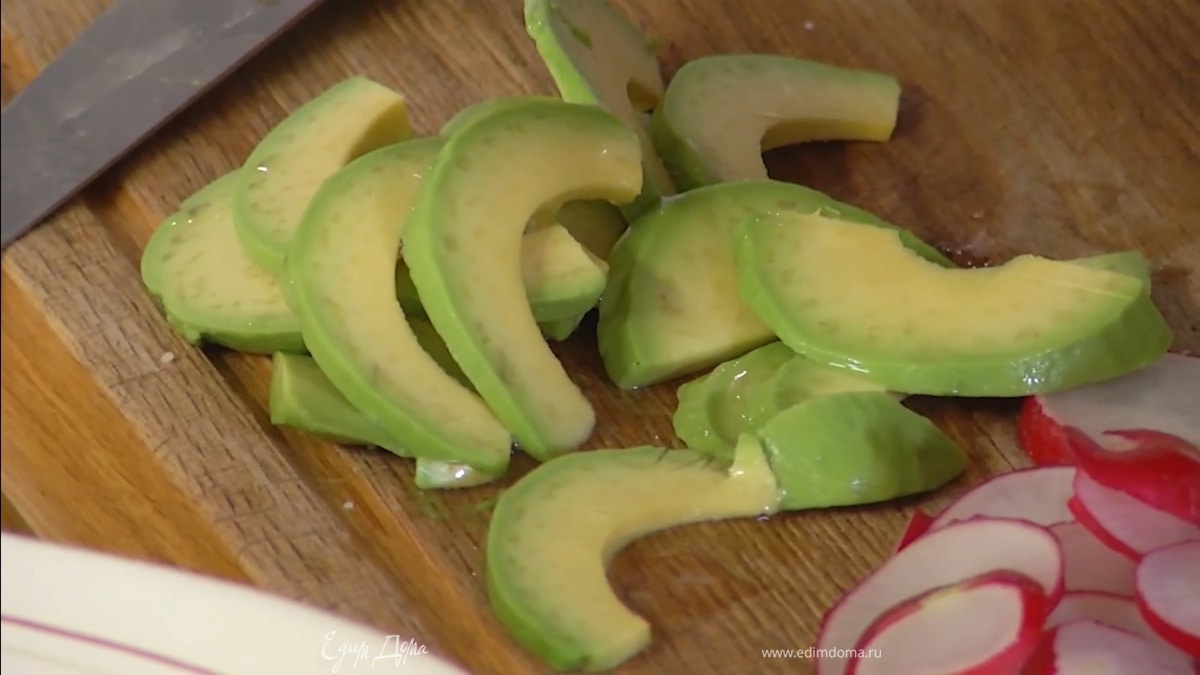 Авокадо почистить и, удалив косточку, нарезать тонкими ломтиками, затем полить соком оставшейся половинки лимона.