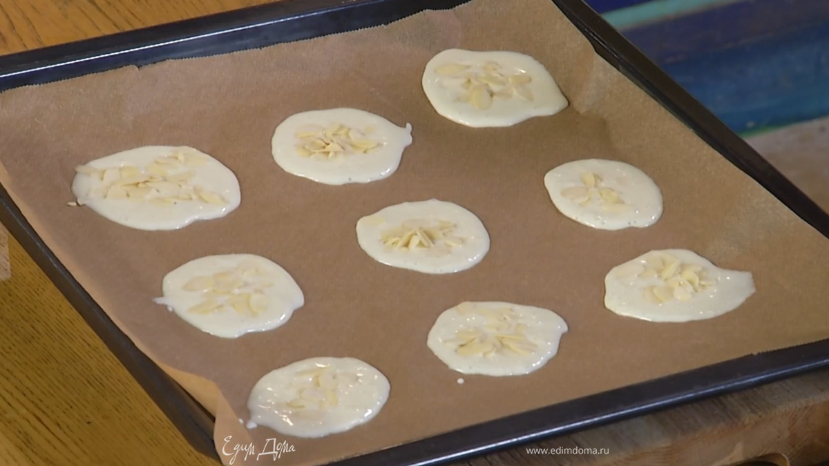 Противень выстелить бумагой для выпечки и разлить тесто небольшими лепешками на некотором расстоянии друг от друга, сверху посыпать хлопьями миндаля.