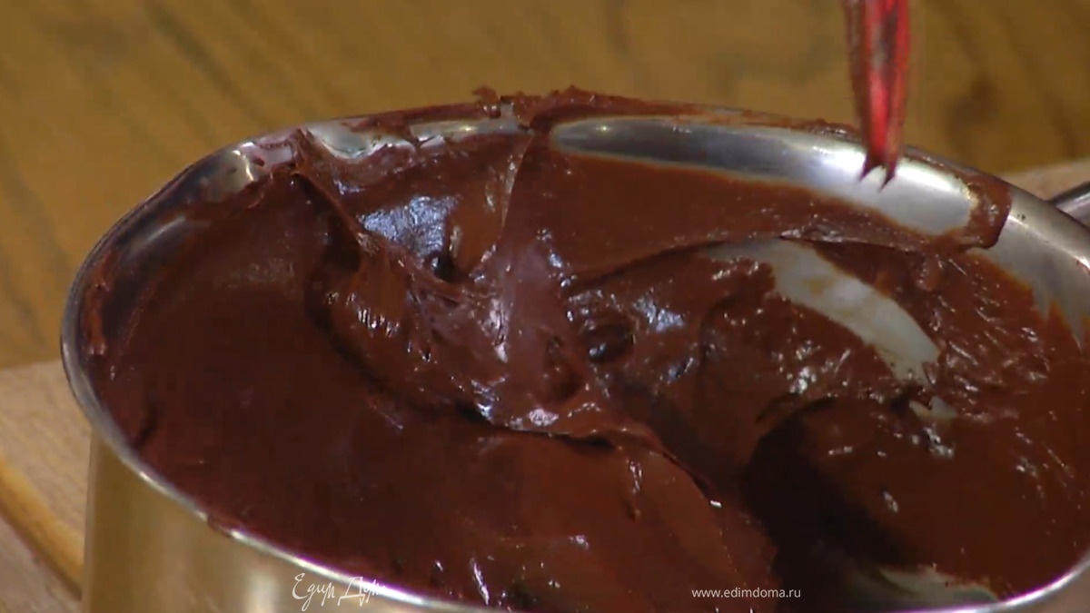 В растопленный шоколад влить немного горячей воды и перемешать, затем добавить яичные желтки и вымешать все лопаткой.