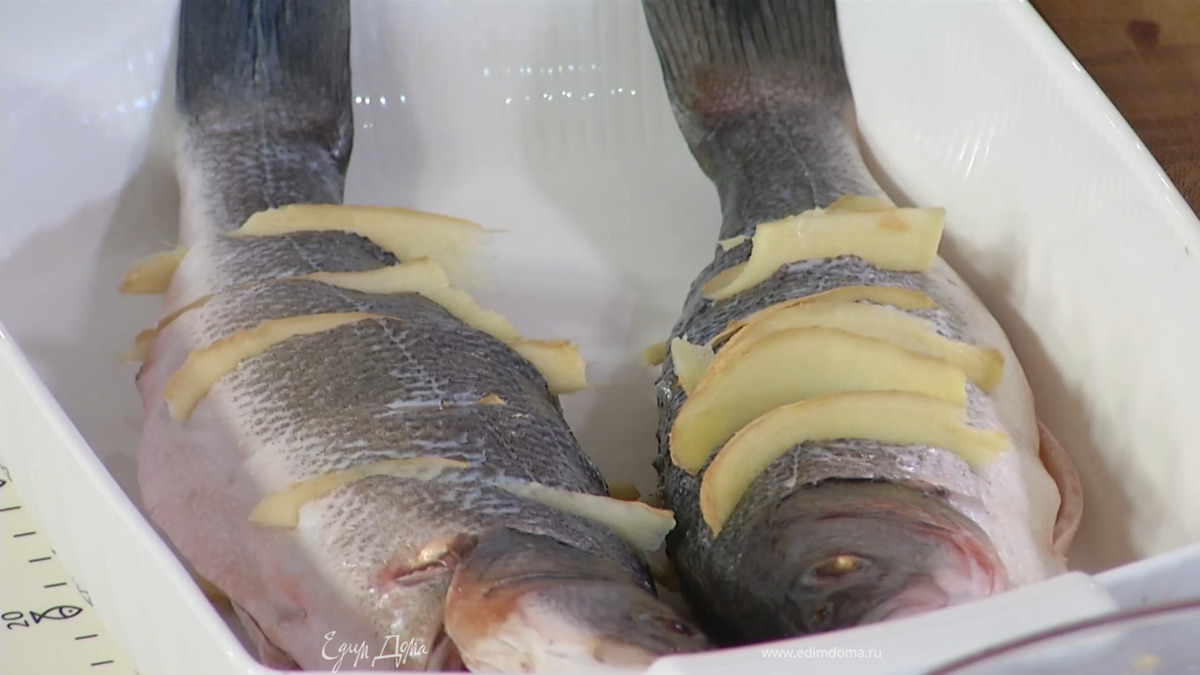 Сделав косые надрезы по бокам дорады, выложить ее в жаропрочную форму, в каждый надрез вставить пластинку имбиря, оставшийся имбирь поместить под рыбу и в брюшко.