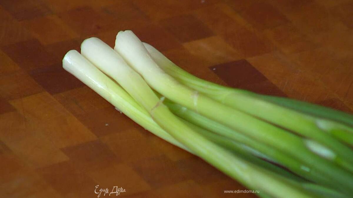Разрезать 2–3 пера зеленого лука на несколько частей.
