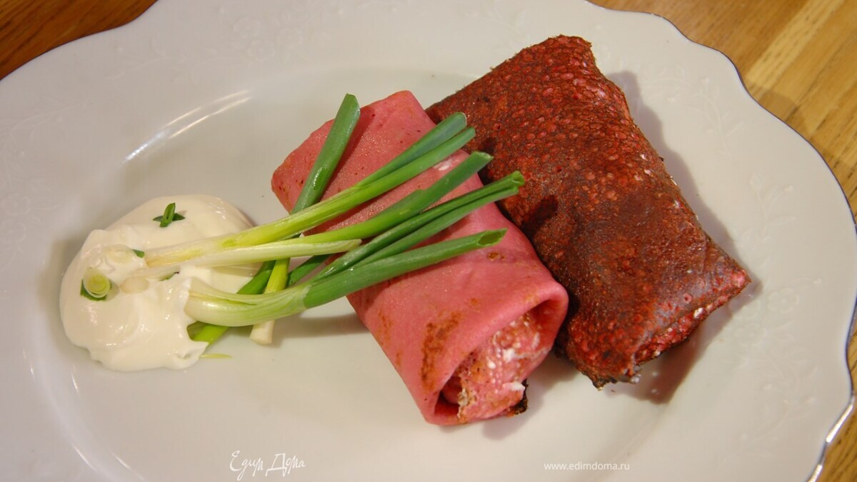 Намазать на блин немного сметаны, выложить зеленый лук и кусочки селедки, свернуть трубочкой или конвертиком.