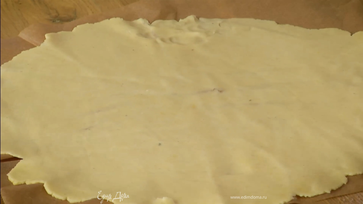 Сформировать из теста шар, затем раскатать его между двумя листами бумаги для выпечки в тонкий пласт.